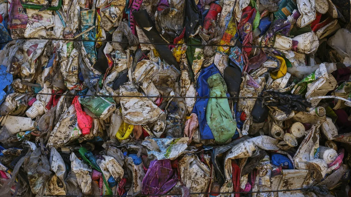 A large pile of garbage beside a metal fence. Stock photograph, not a Pakistani site.