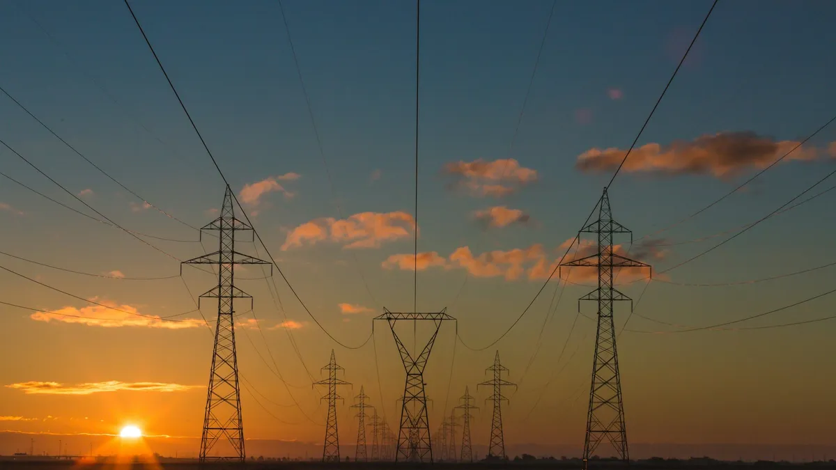 Electricity transmission towers and power lines at sunset.