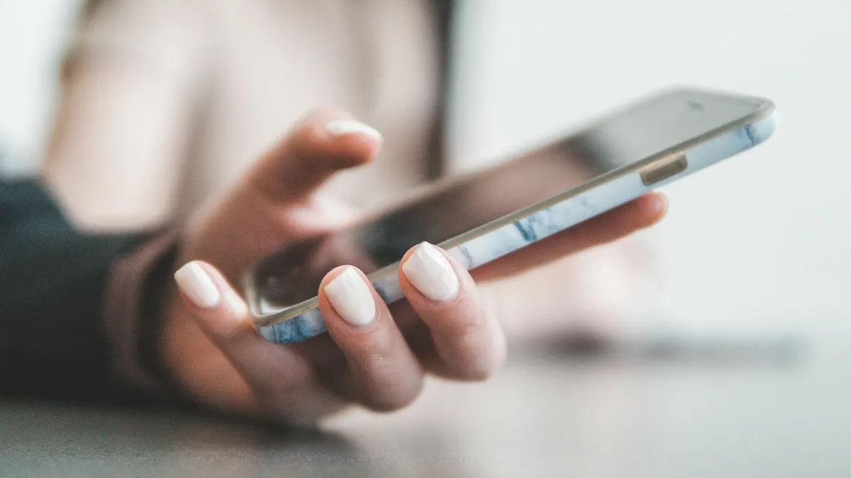A person's hand holding a smartphone, screen tilted away from the camera.