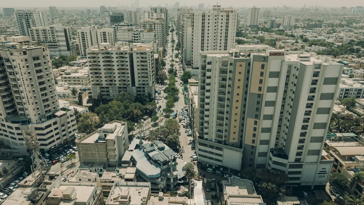 Apartment towers lining a tree-lined road in Karachi, seen from above.