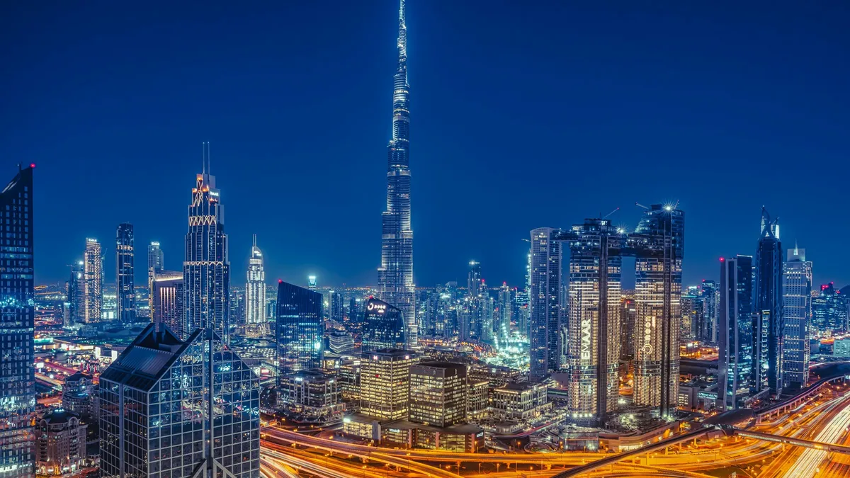 The Dubai skyline at night, with the Burj Khalifa above lit office towers and highways.