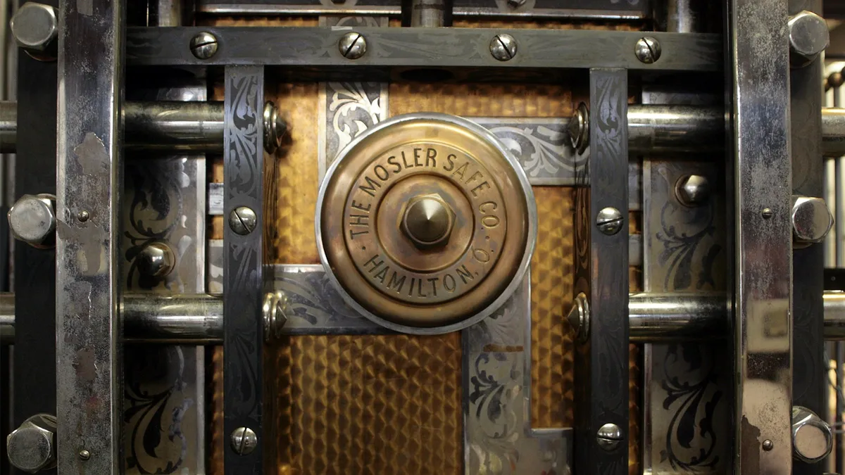 The brass dial and steel bolts of an old bank vault door.