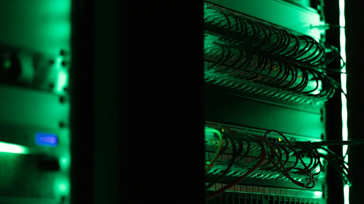 Network cables in a server rack, lit green in a dark room.