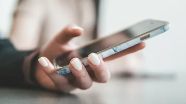 A person's hand holding a smartphone, screen tilted away from the camera.