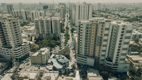 Apartment towers lining a tree-lined road in Karachi, seen from above.