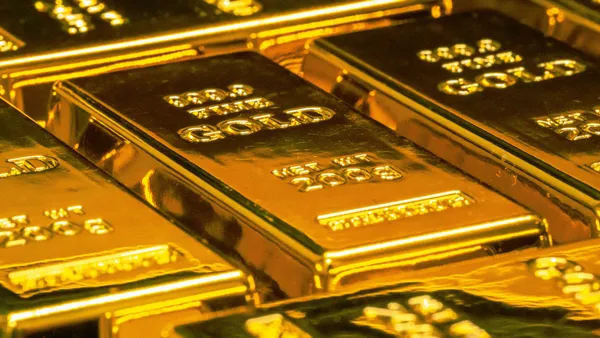 Stacked gold bars under warm light.