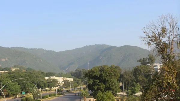 A tree-lined avenue in Islamabad with the Margalla Hills behind.